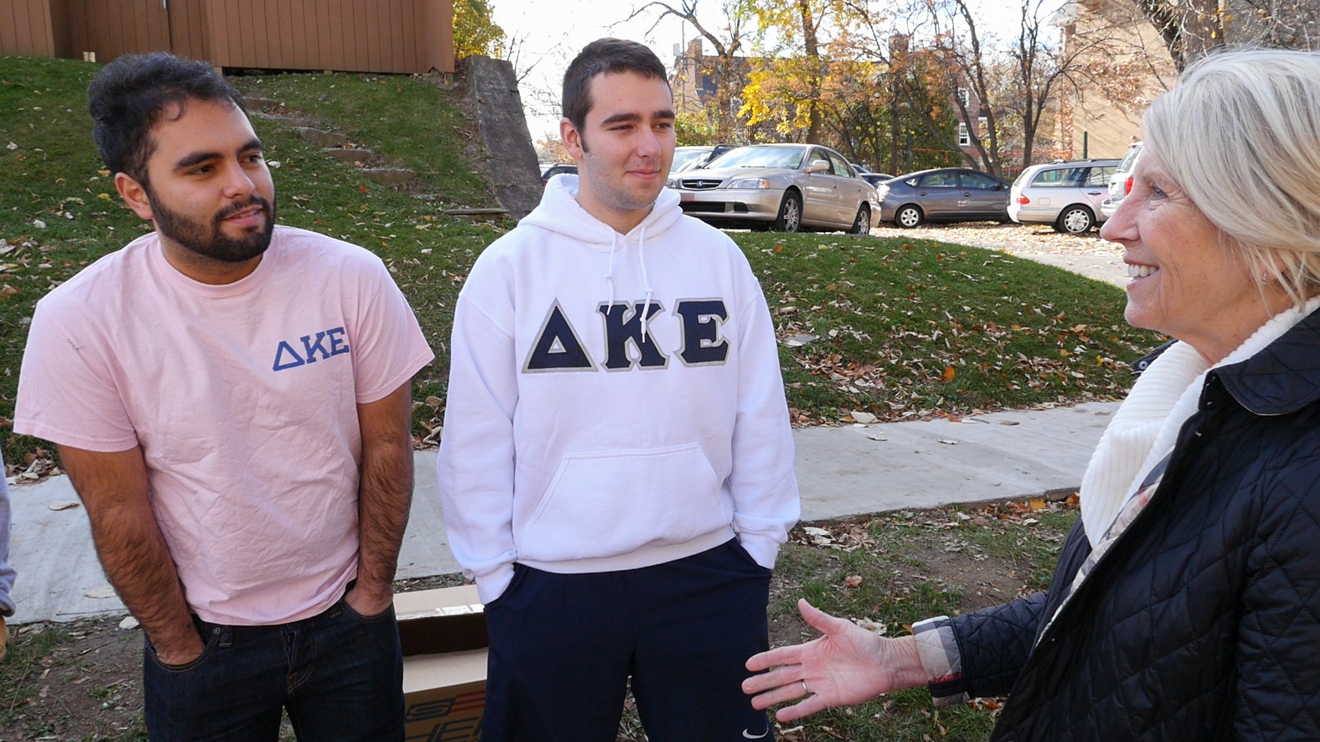 Peg Hambrick extends her hand to greet two fraternity members in her neighborhood